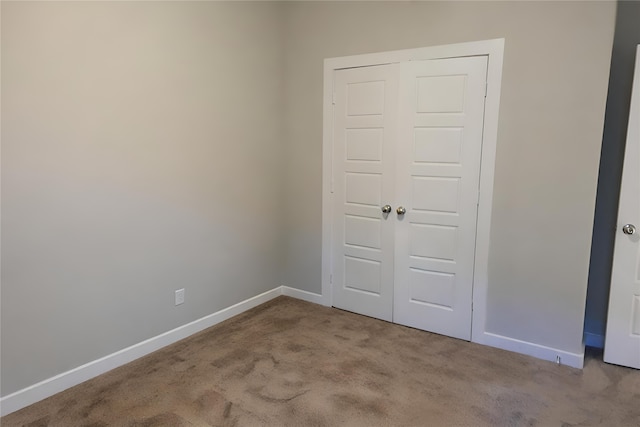 unfurnished bedroom featuring light colored carpet and a closet