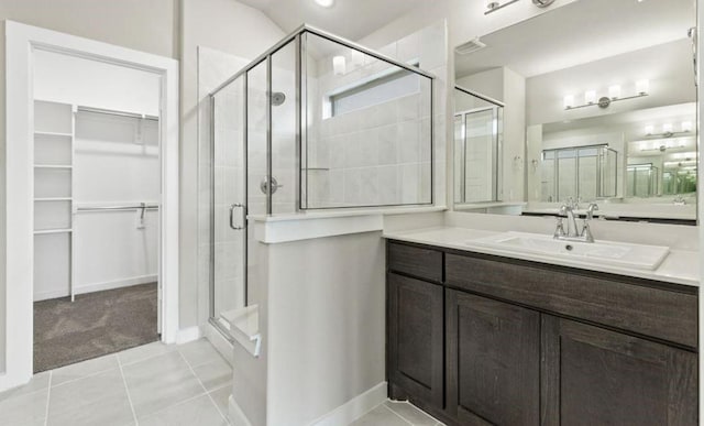 bathroom with walk in shower, vanity, and tile patterned flooring