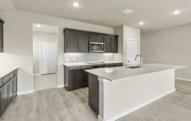 kitchen featuring tasteful backsplash, sink, an island with sink, and black electric stovetop