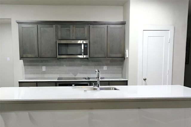 kitchen with dark brown cabinets, sink, an island with sink, and decorative backsplash