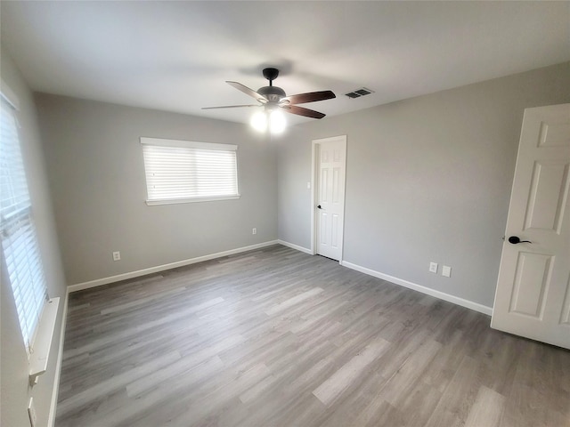 empty room with a ceiling fan, baseboards, visible vents, and light wood finished floors