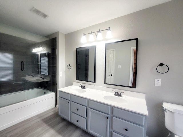 bathroom featuring enclosed tub / shower combo, visible vents, a sink, and toilet