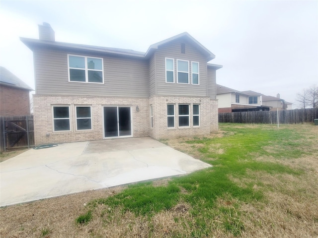 back of property with a yard, a patio area, brick siding, and fence