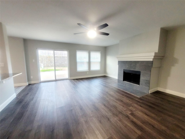 unfurnished living room with a ceiling fan, a fireplace, baseboards, and dark wood-type flooring