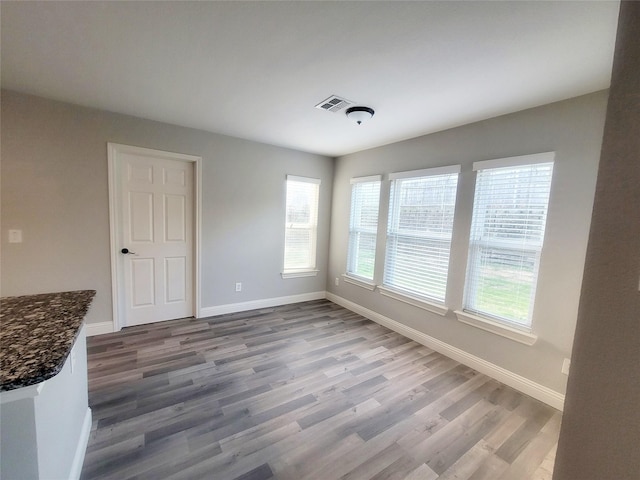 unfurnished room featuring dark wood finished floors, visible vents, and baseboards