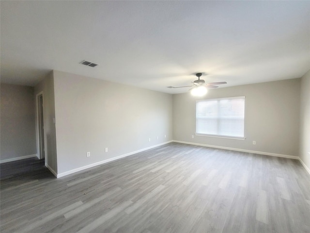 spare room with baseboards, visible vents, ceiling fan, and wood finished floors