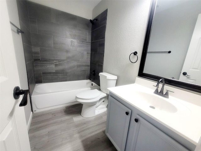 full bathroom with a textured wall, toilet, wood finished floors, bathing tub / shower combination, and vanity