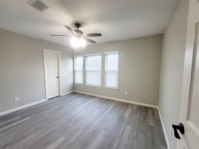 empty room with visible vents, ceiling fan, baseboards, and wood finished floors