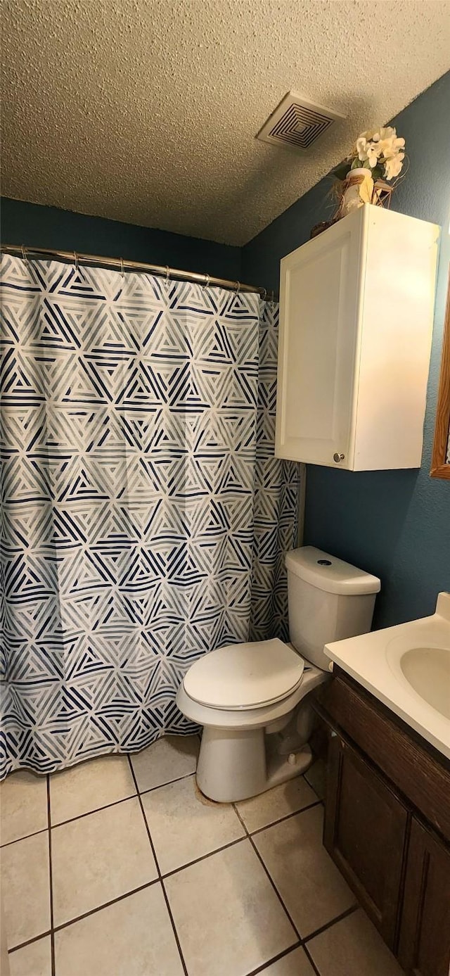 bathroom with toilet, a textured ceiling, and tile patterned floors