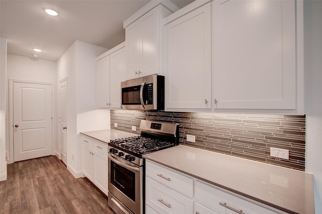 kitchen featuring appliances with stainless steel finishes, light wood-type flooring, white cabinetry, and backsplash