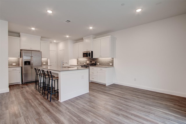 kitchen featuring a center island with sink, white cabinets, stainless steel appliances, and sink