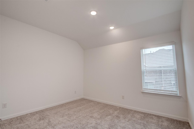 carpeted spare room with lofted ceiling