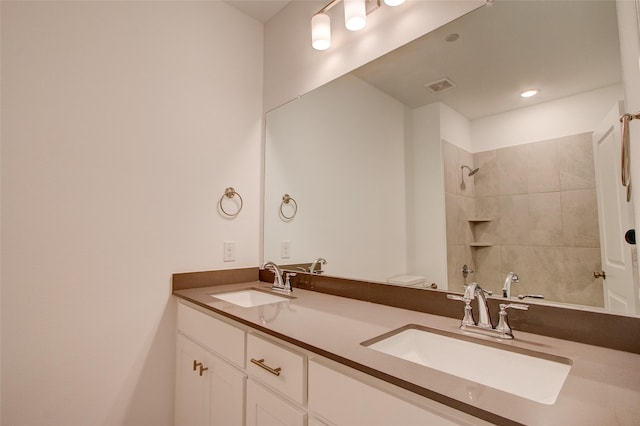 bathroom with tiled shower, vanity, and toilet