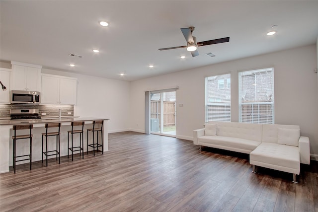 living room featuring light hardwood / wood-style flooring, ceiling fan, and sink