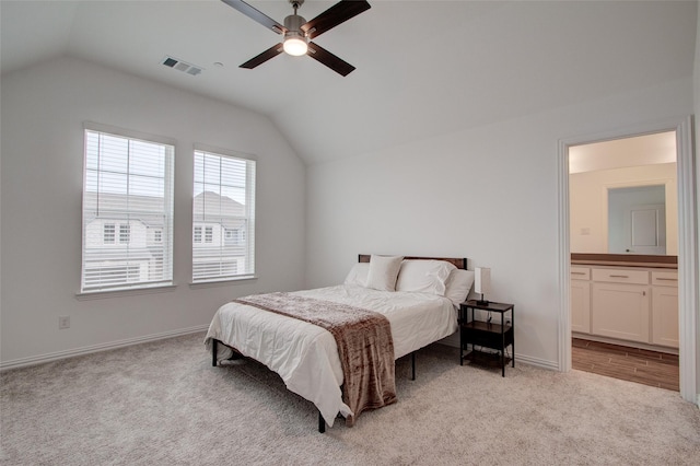 bedroom featuring light carpet, connected bathroom, vaulted ceiling, and ceiling fan