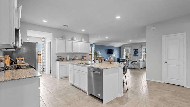 kitchen featuring dishwasher, sink, light stone countertops, an island with sink, and white cabinetry