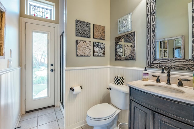 bathroom featuring tile patterned flooring, vanity, toilet, and a shower with shower door