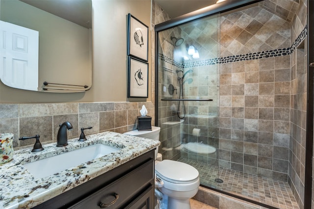 bathroom featuring walk in shower, backsplash, toilet, vanity, and tile walls