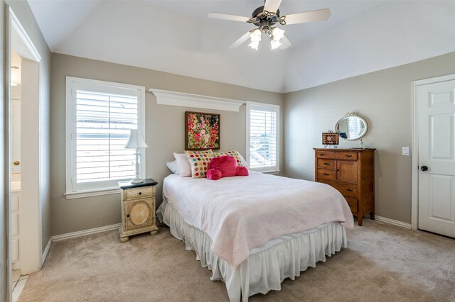 bedroom featuring ceiling fan, ensuite bathroom, light carpet, and vaulted ceiling