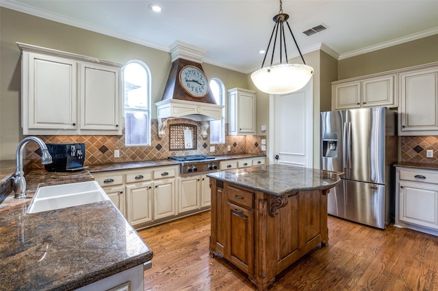 kitchen with a center island, crown molding, sink, hanging light fixtures, and stainless steel appliances