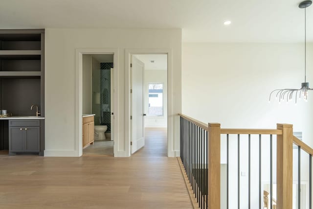 hall featuring built in shelves, sink, and light hardwood / wood-style flooring