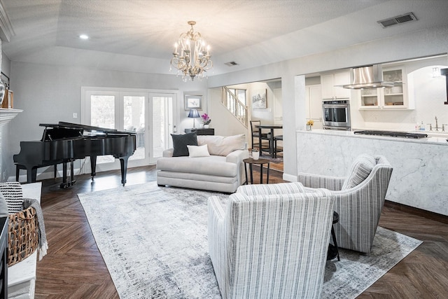 living room with a notable chandelier, dark parquet floors, a raised ceiling, and a textured ceiling