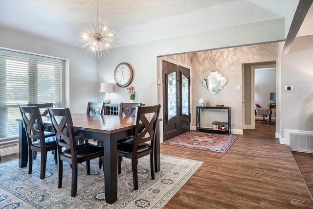 dining space with french doors, dark wood-type flooring, and a notable chandelier