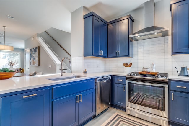 kitchen featuring wall chimney exhaust hood, blue cabinets, sink, hanging light fixtures, and stainless steel appliances