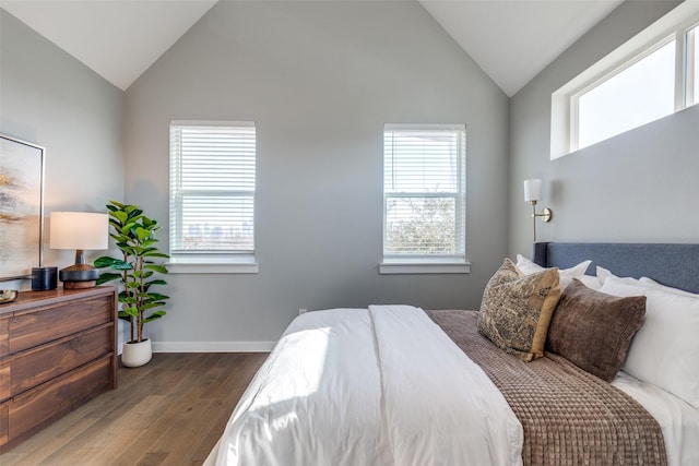 bedroom featuring multiple windows, dark wood-type flooring, and vaulted ceiling