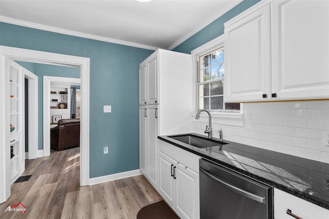 kitchen with white cabinetry, stainless steel dishwasher, dark stone counters, and sink