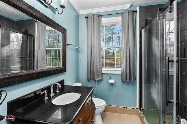 bathroom featuring a shower with shower door, vanity, toilet, crown molding, and tile patterned floors