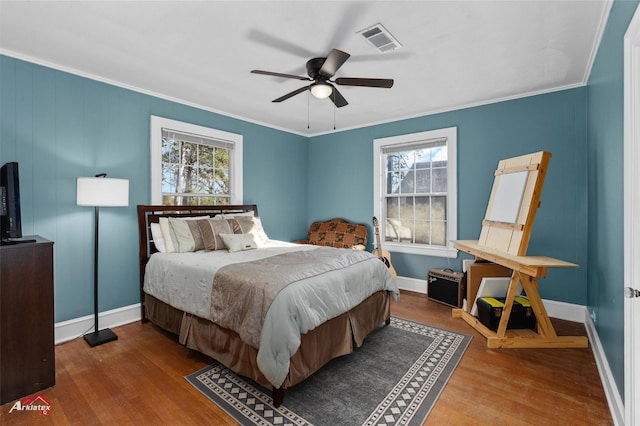 bedroom with multiple windows, wood-type flooring, ornamental molding, and ceiling fan