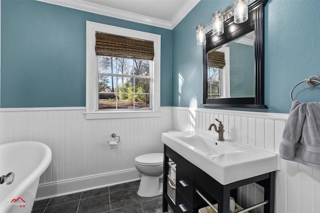 bathroom featuring a tub to relax in, tile patterned flooring, vanity, toilet, and crown molding