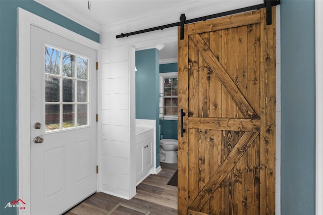 doorway to outside with a barn door, dark hardwood / wood-style floors, and ornamental molding