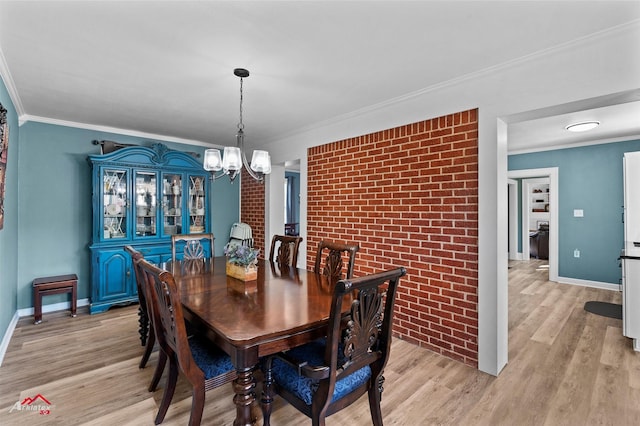 dining space featuring light wood-type flooring, ornamental molding, brick wall, and a chandelier