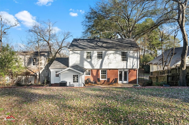 rear view of house with a lawn, cooling unit, a patio, and french doors