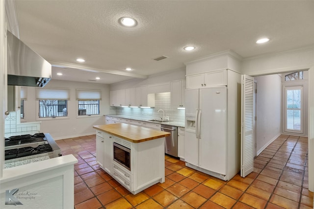 kitchen with white cabinets, stainless steel appliances, and wood counters