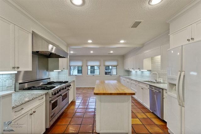 kitchen with wood counters, appliances with stainless steel finishes, a center island, and white cabinetry