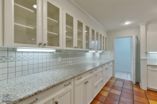 kitchen featuring white cabinetry, decorative backsplash, light stone countertops, and ornamental molding