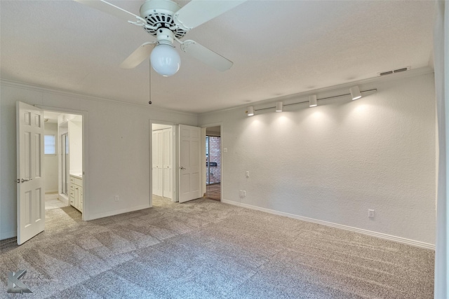 carpeted spare room with track lighting, ceiling fan, and ornamental molding