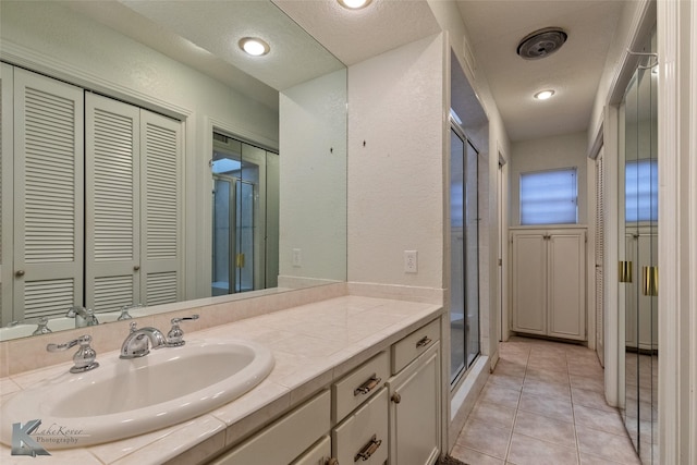 bathroom featuring tile patterned flooring, vanity, and a shower with door