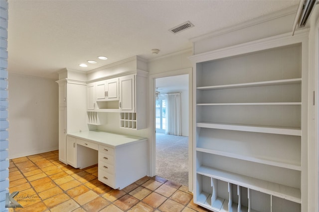 kitchen featuring light carpet, crown molding, white cabinets, and a textured ceiling