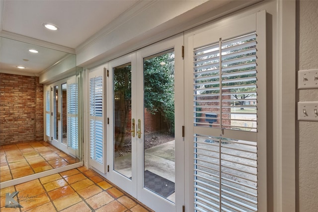 doorway with french doors, brick wall, and ornamental molding