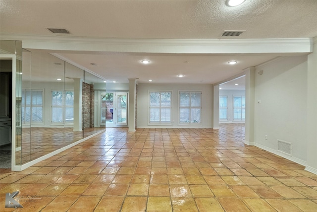 empty room with light tile patterned floors, a textured ceiling, and ornamental molding