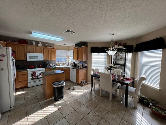 kitchen featuring pendant lighting, white appliances, a center island, and light tile patterned flooring