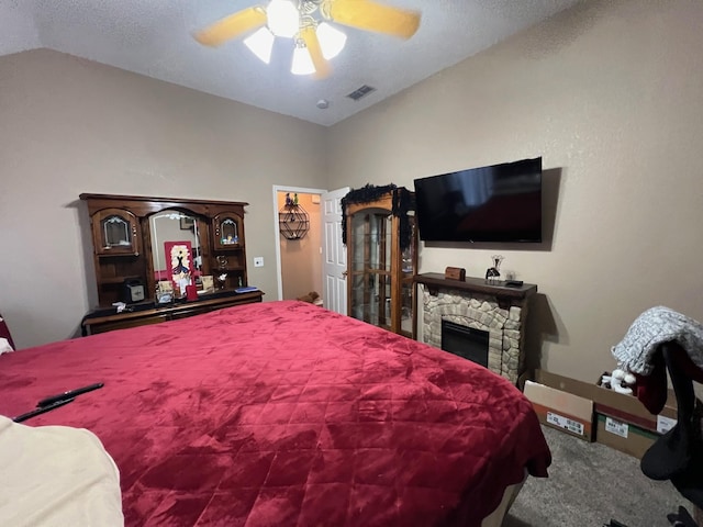 carpeted bedroom with lofted ceiling, a stone fireplace, and ceiling fan