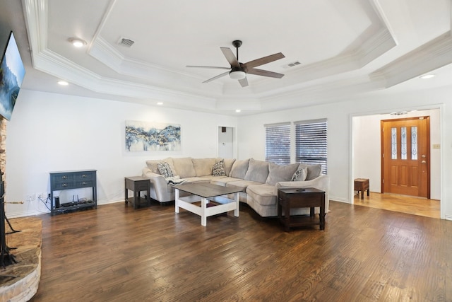 living room with dark hardwood / wood-style floors, ornamental molding, and a tray ceiling