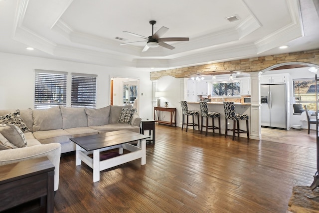 living room featuring crown molding, a tray ceiling, dark hardwood / wood-style floors, and ceiling fan