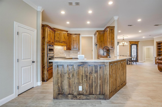 kitchen with double oven, sink, hanging light fixtures, ornamental molding, and light hardwood / wood-style flooring