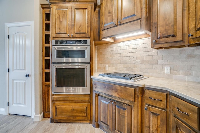 kitchen featuring appliances with stainless steel finishes, light wood-type flooring, and backsplash